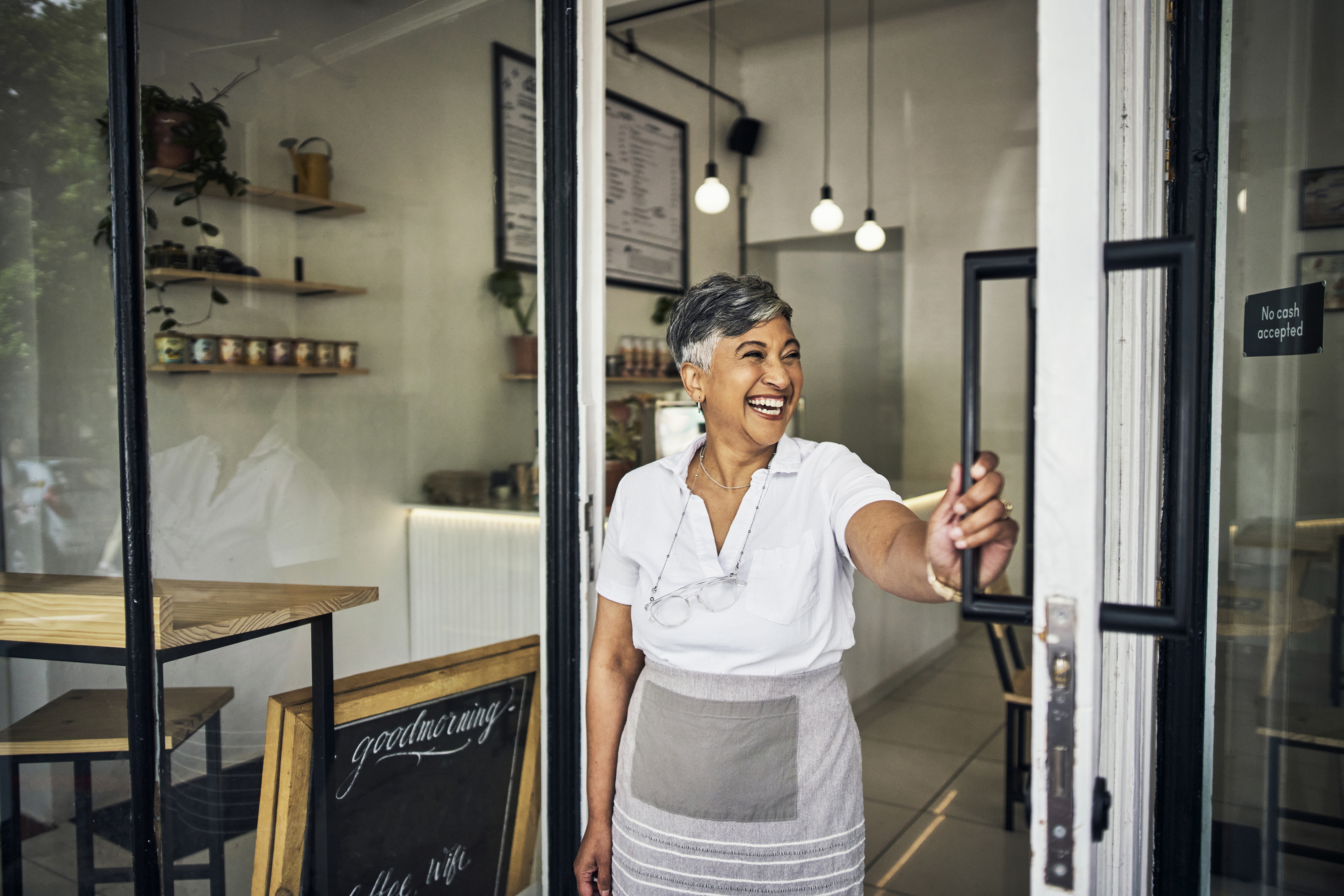 Business owner smiles and opens the front door to the store